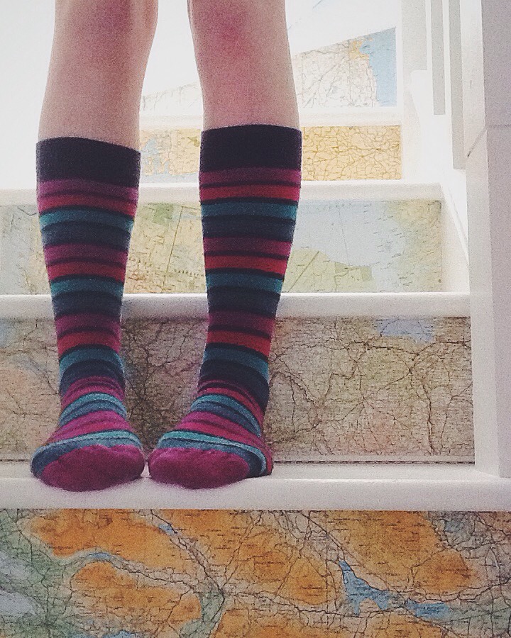 Feet in stripy socks standing on stairs with maps on risers.